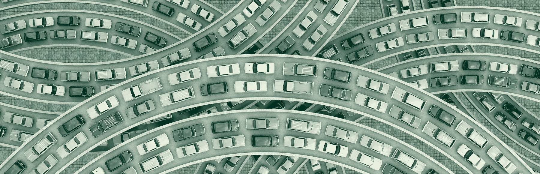 Aerial view of vehicles queued nose to tail along the curving ramps of a multi-level highway interchange.